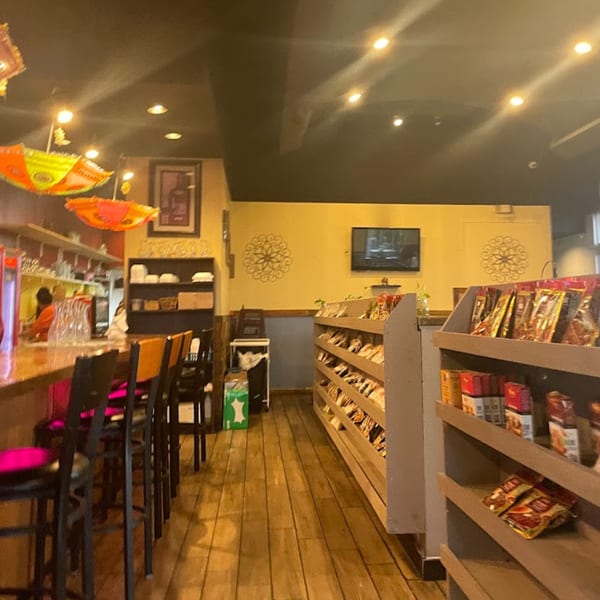 Interior of Dakshin Indian Bistro with a bar, stools, and shelves of Indian groceries.