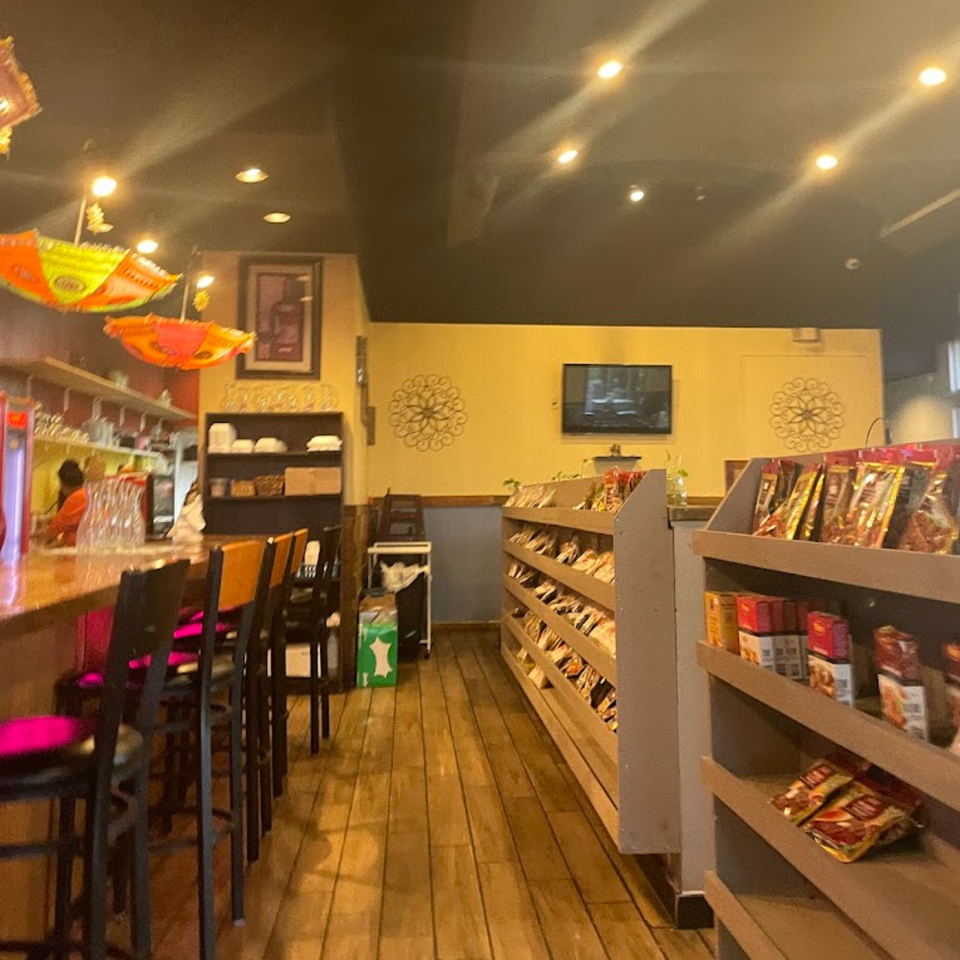 Interior of Dakshin Indian Bistro with a bar, stools, and shelves of Indian groceries.