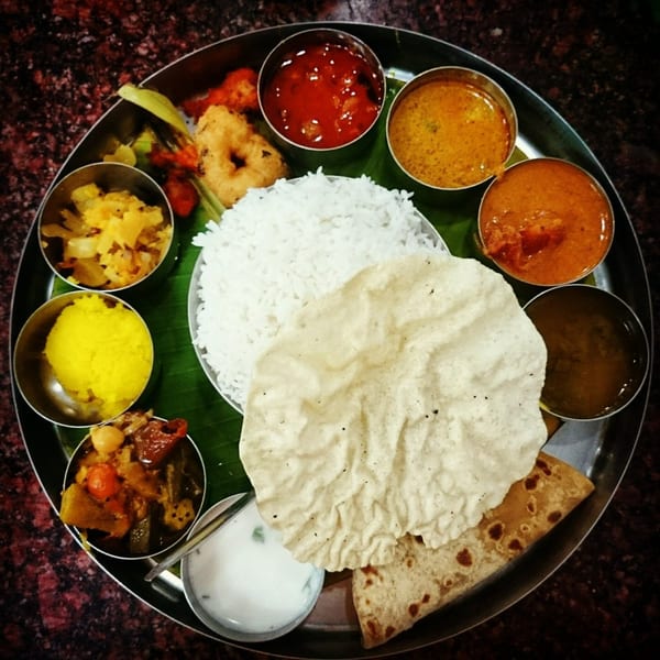 A Dakshin Indian Bistro thali with rice, curries, papadum, and other dishes on a banana leaf.